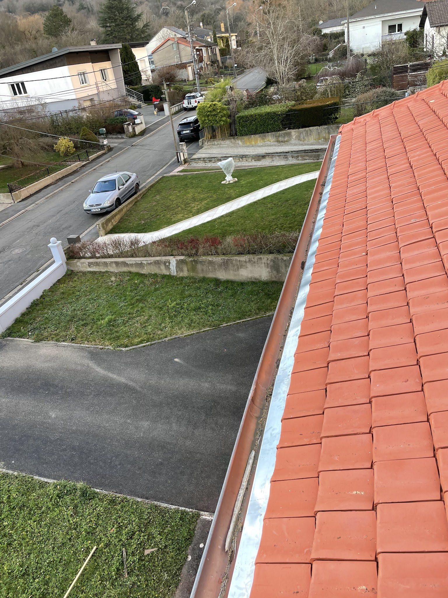 Toiture en tuiles neuves et sa gouttière, vue depuis le toit