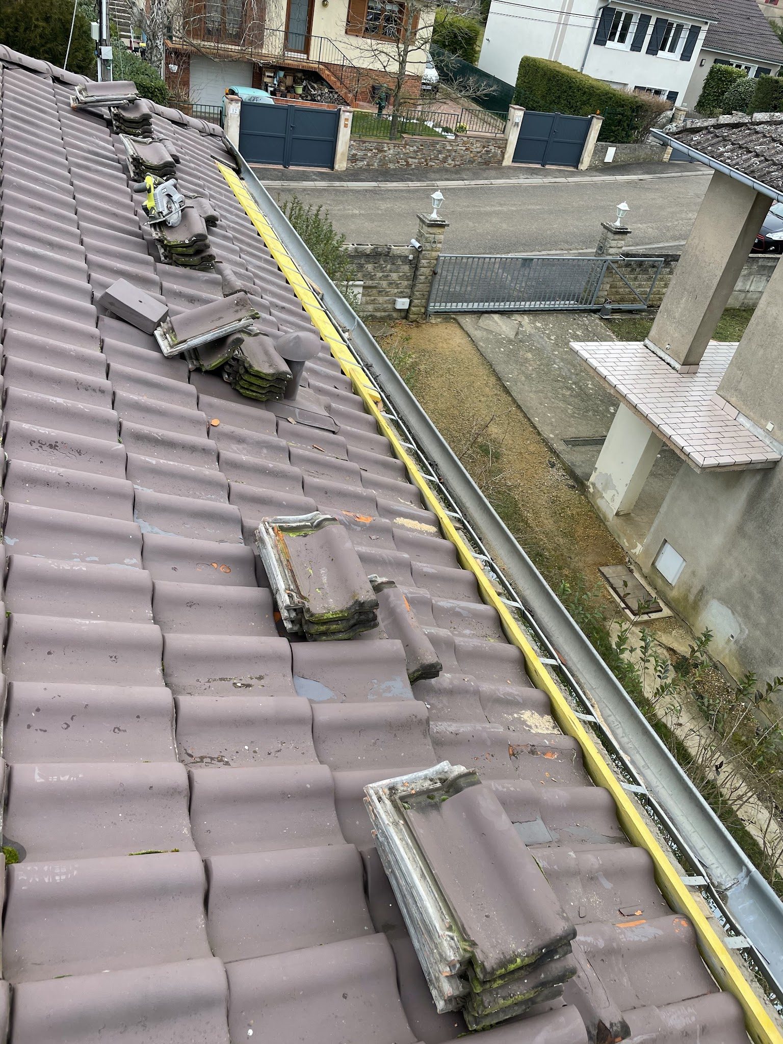 Toiture en cours de travaux, tuiles déposées le long du liteau