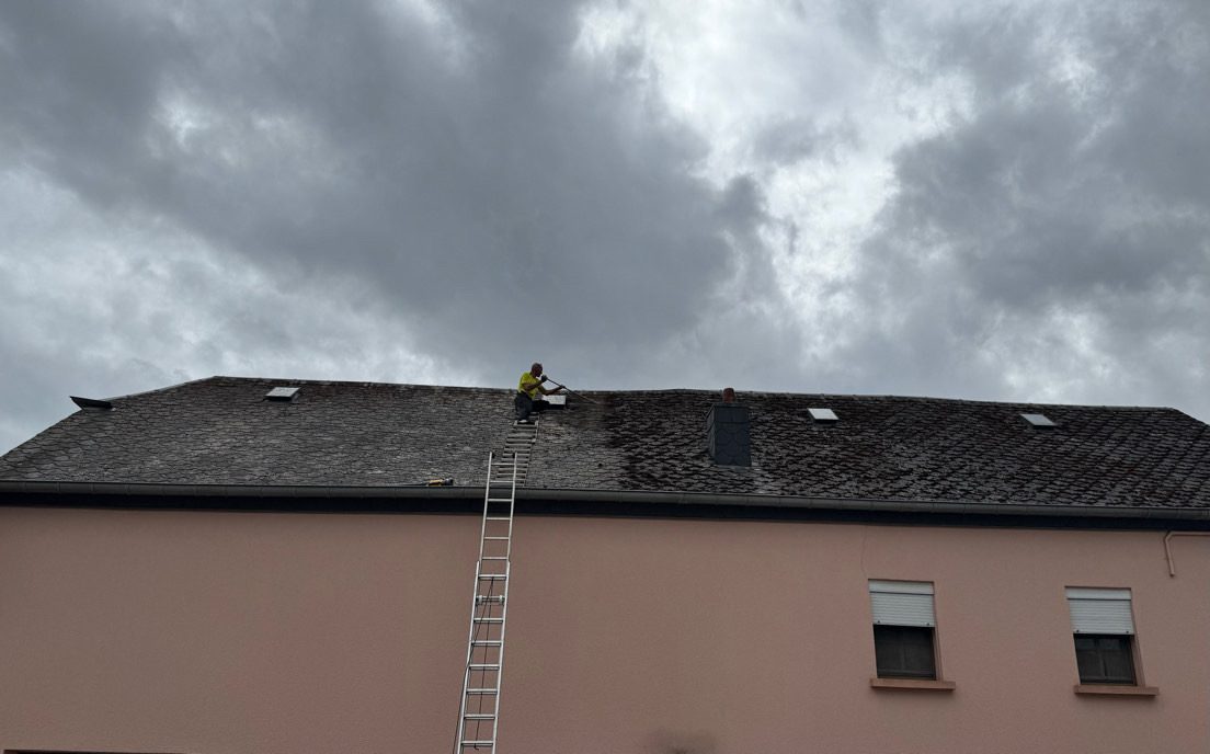 Couvreur au travail sur un toit en ardoise sous un ciel chargé